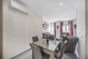 Ein modernes Wohnzimmer mit einem Glastisch, bequemen Sitzgelegenheiten, einer Couch und einem roten Vorhang.