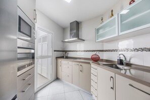 Eine moderne Küche mit Mikrowelle, Backofen und einer Edelstahl-Dunstabzugshaube.