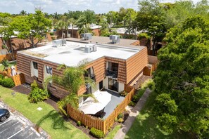 Ein modernes Gebäude mit flachem Dach, mehreren Klimaanlagen und einem eingezäunten Innenhof.