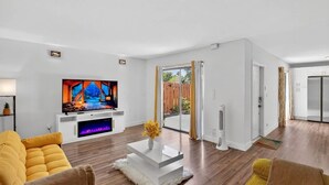 Een moderne woonkamer met een flatscreen televisie, een witte salontafel en een gele bank.