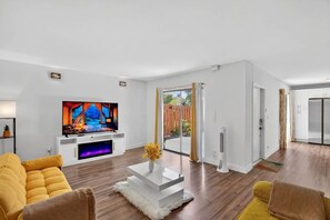 Ein modernes Wohnzimmer mit einem Flachbildfernseher, einem weißen Couchtisch und einem gelben Sofa.