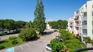 Ein mehrgeschossiges Wohngebäude mit Balkonen, einem Parkplatz und umliegender Bepflanzung.