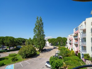 Ein mehrgeschossiges Wohngebäude mit Balkonen, einem Parkplatz und umliegender Bepflanzung.