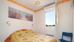 Ein Schlafzimmer mit Bett, Stuhl, Fenster und einem Bild an der Wand.