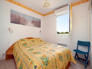 Ein Schlafzimmer mit Bett, Stuhl, Fenster und einem Bild an der Wand.