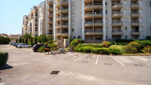 Ein mehrstöckiges Wohnhaus mit Balkonen, einem Parkplatz und Grünflächen.