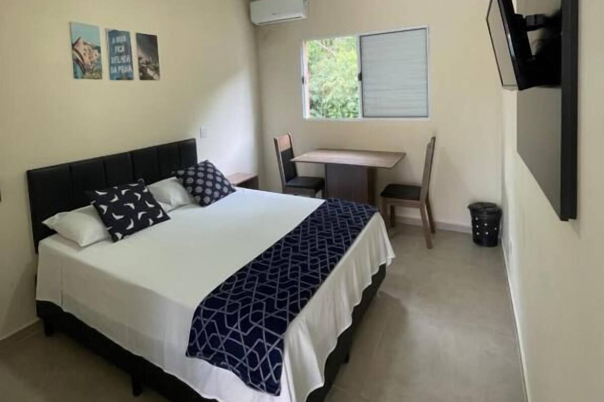 Een slaapkamer met een bed, een bureau, een stoel, een airconditioning en een raam.