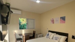A bedroom with a bed, a desk, a chair, and a small table. - Residencial 220 Maresias (São Sebastião)