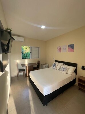A bedroom with a bed, a desk, and a chair. - Residencial 220 Maresias (São Sebastião)