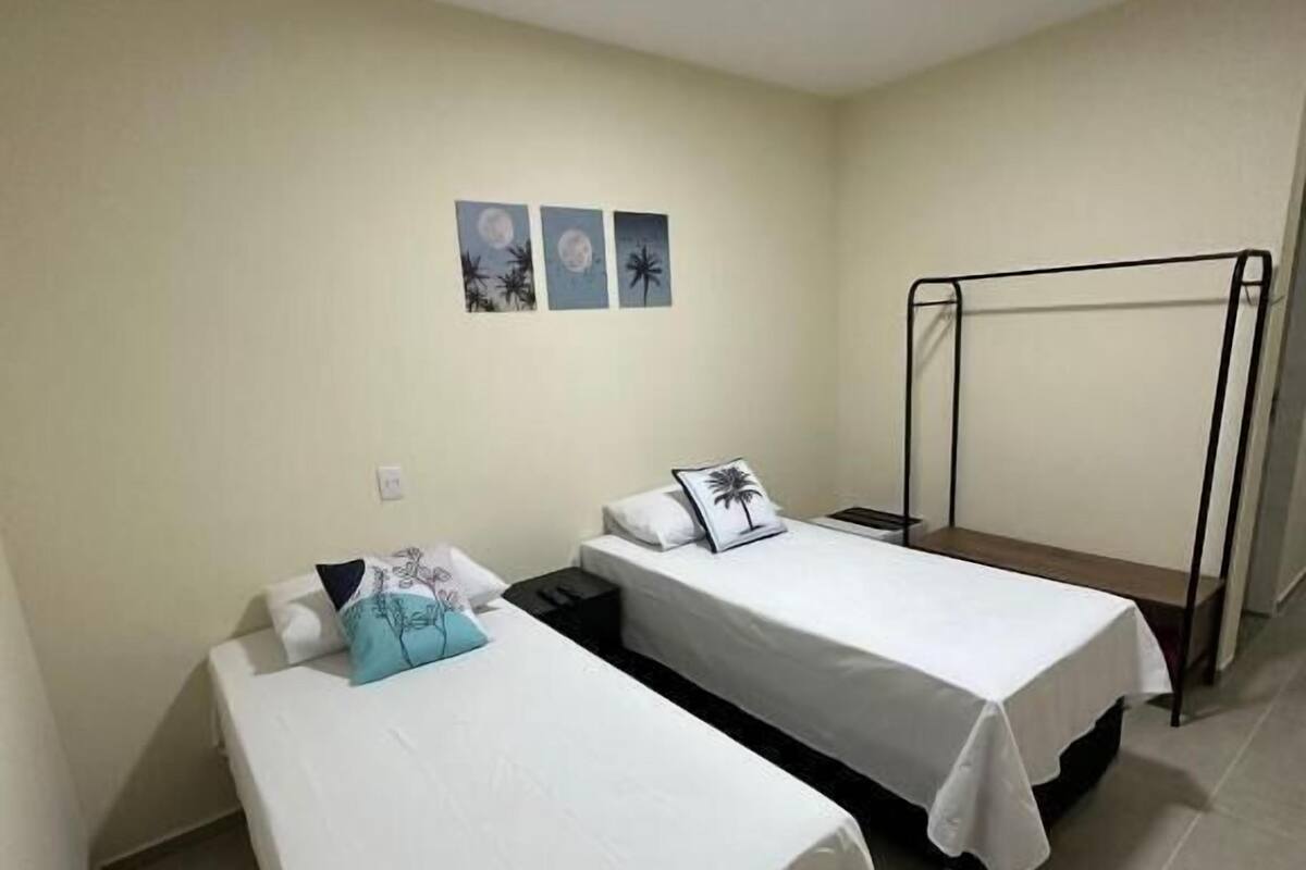 Een kamer met twee eenpersoonsbedden, een klein tafeltje en een metalen rek.