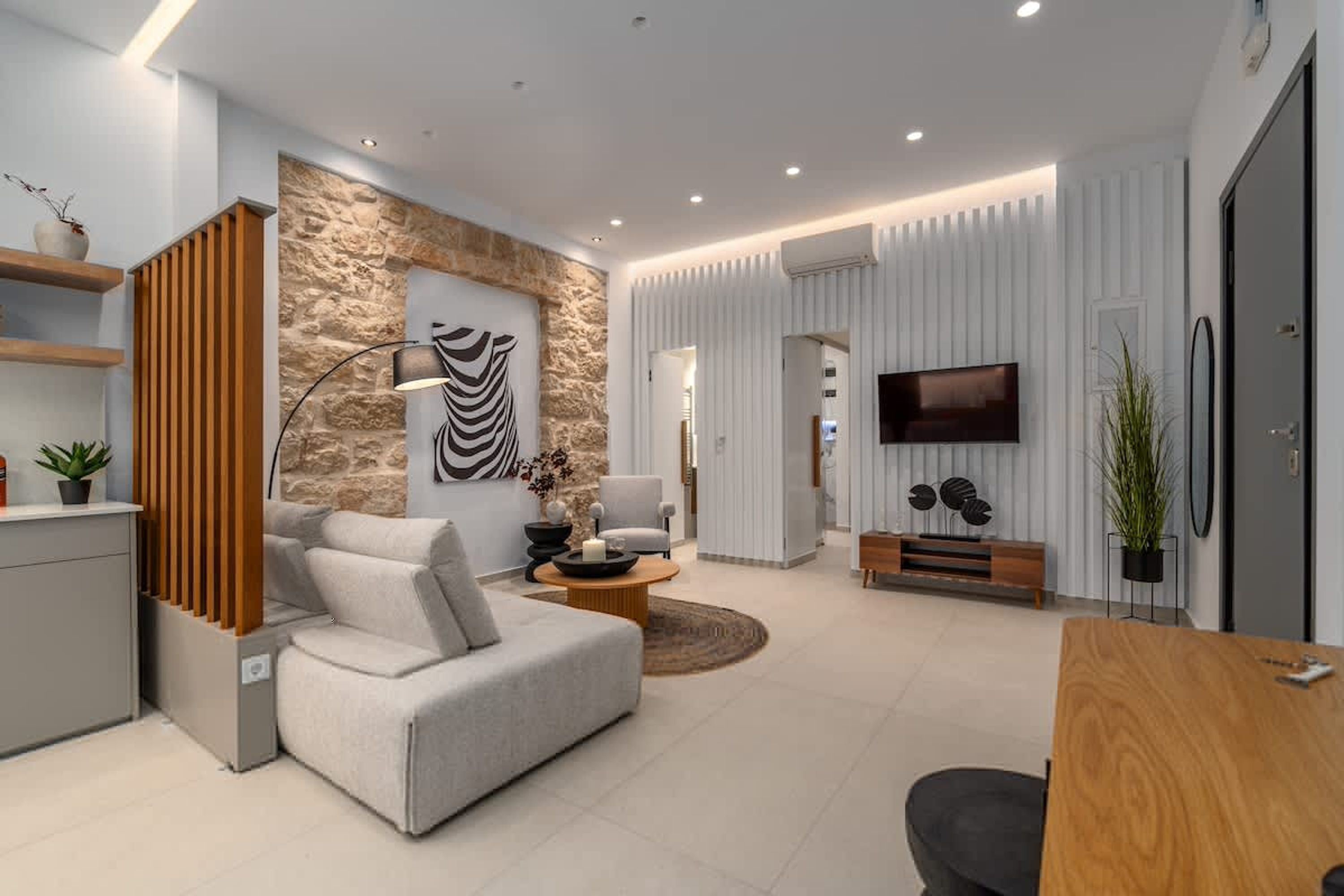 A modern living room with a sofa, a coffee table, a TV, and a stone accent wall.