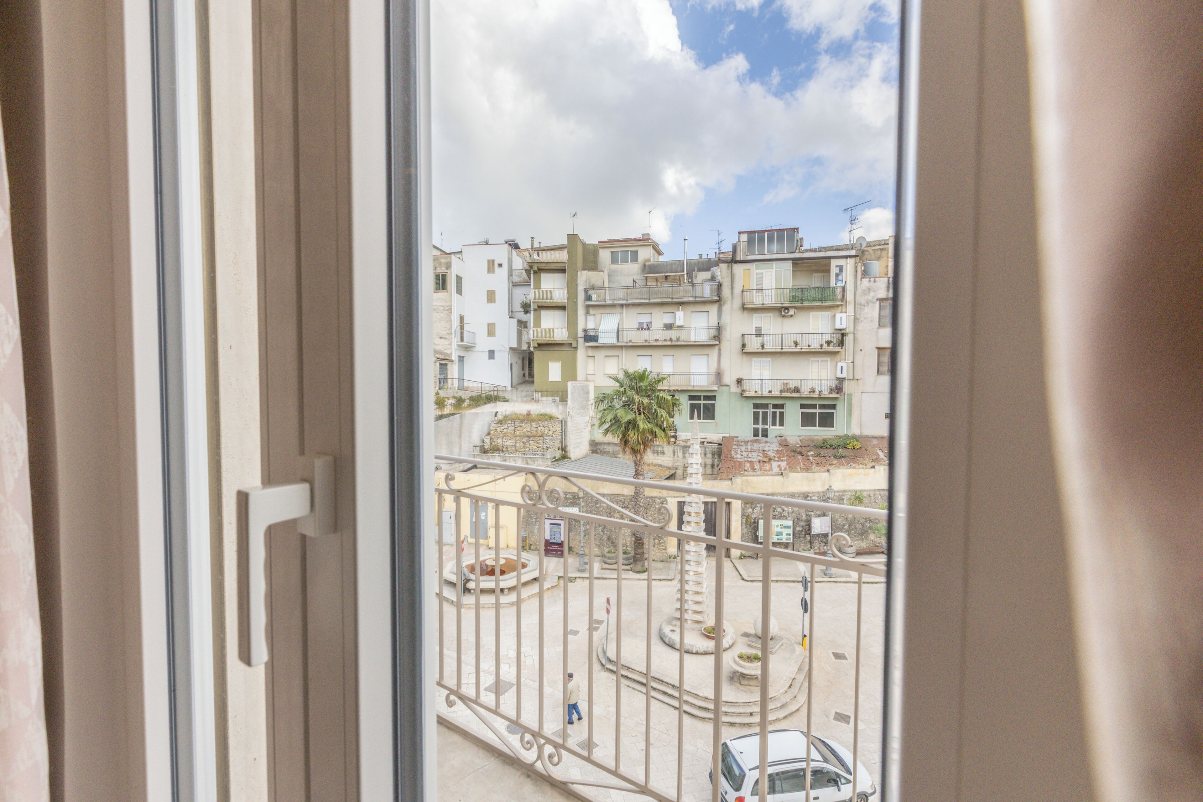 A balcony with a view of a cityscape, including buildings and a palm tree.