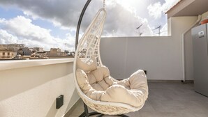 Un fauteuil suspendu sur une terrasse sur le toit, offrant une vue sur le paysage urbain.