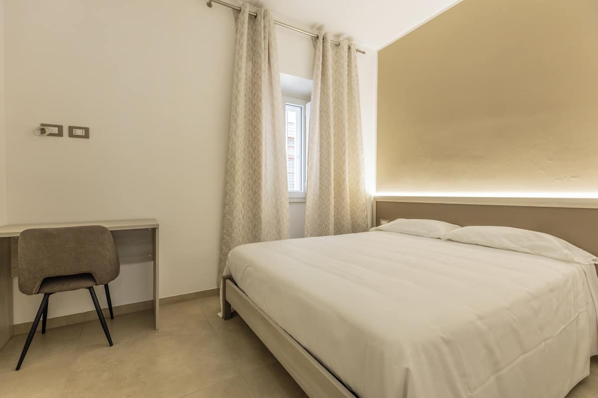 A bedroom with a bed, a desk, and a chair.