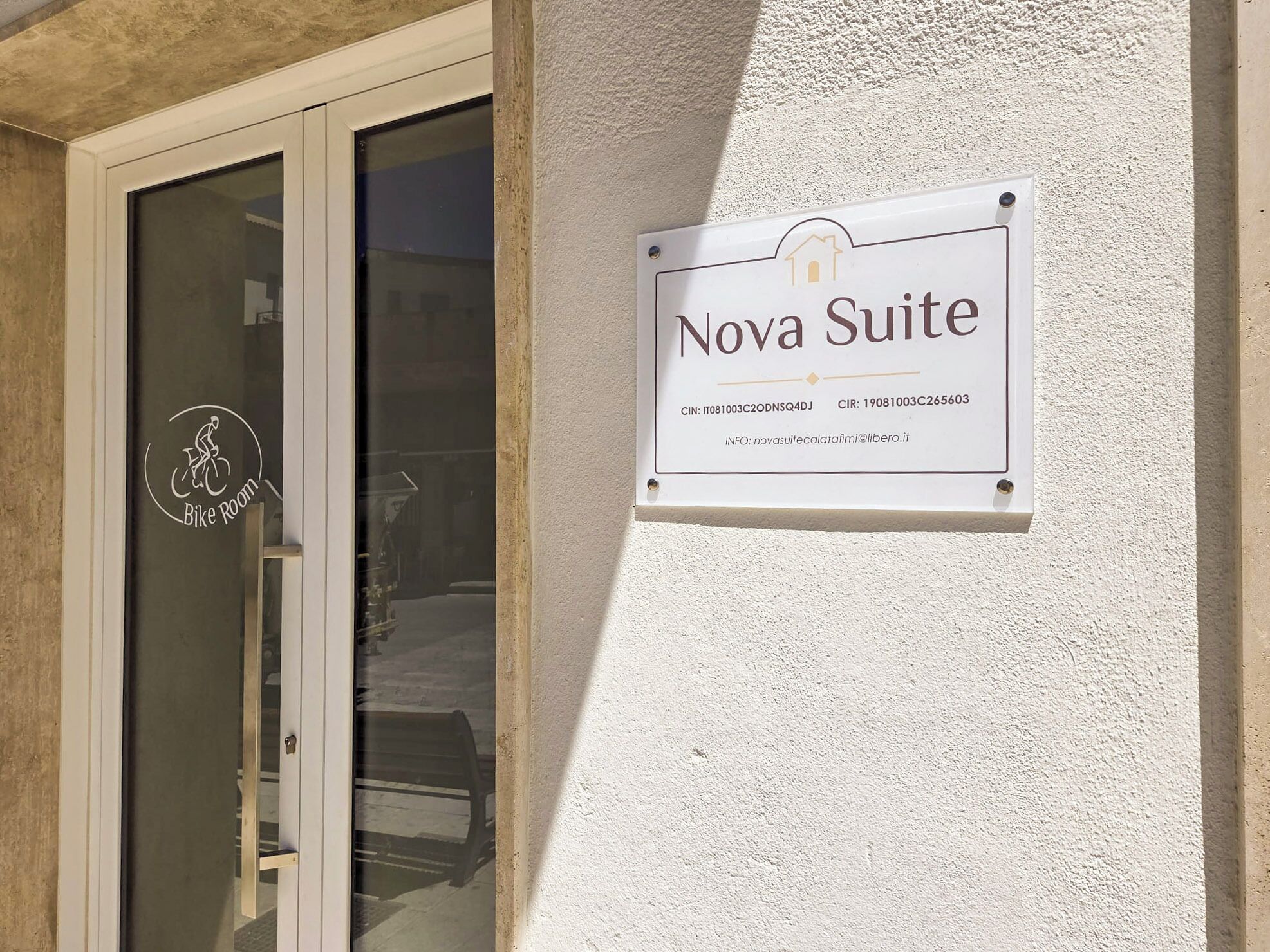 A sign for 'Nova Suite' with contact information and a logo for 'Bike Room' on a building's glass door.