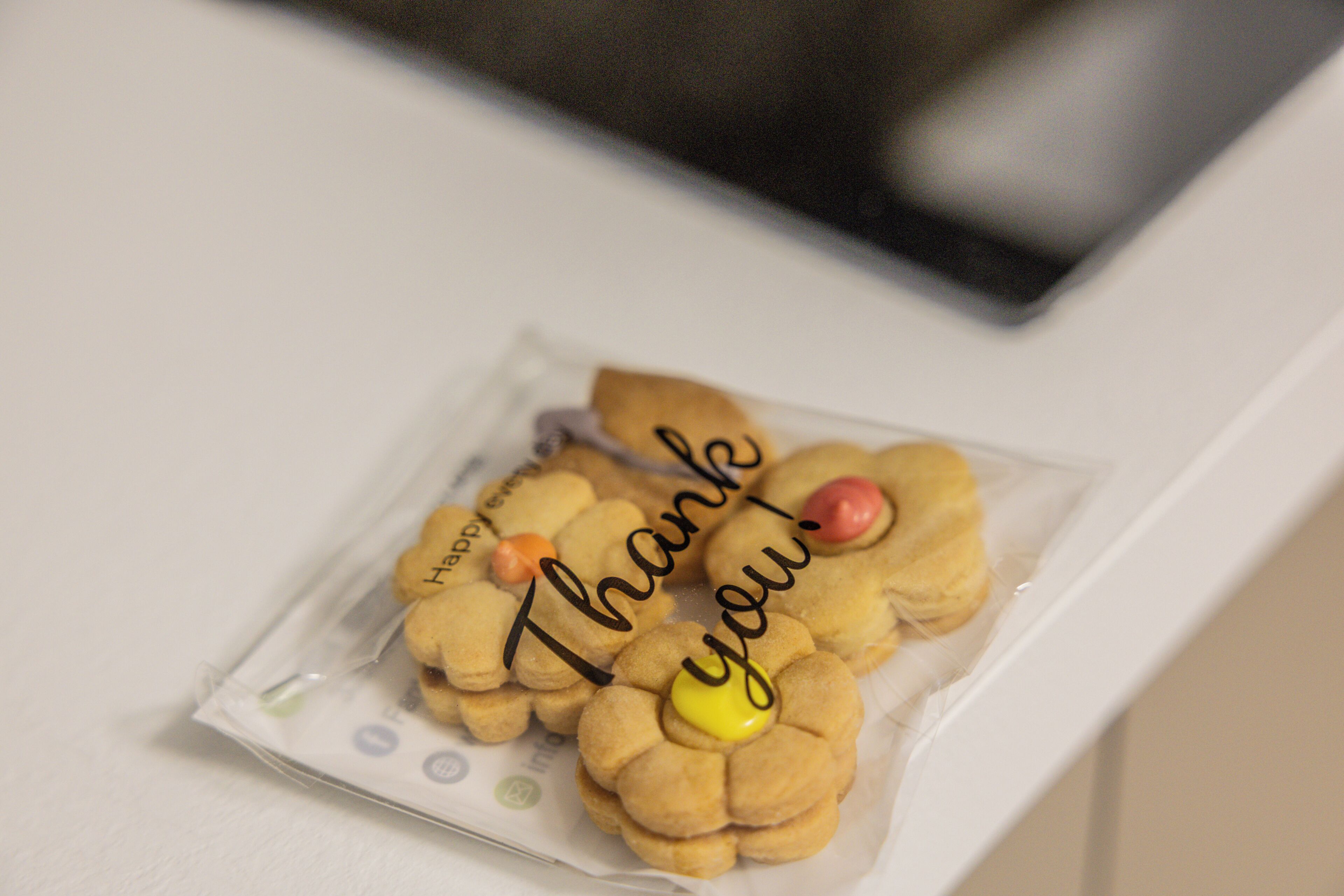 A package containing cookies shaped like flowers with 'Thank you!' written on them.