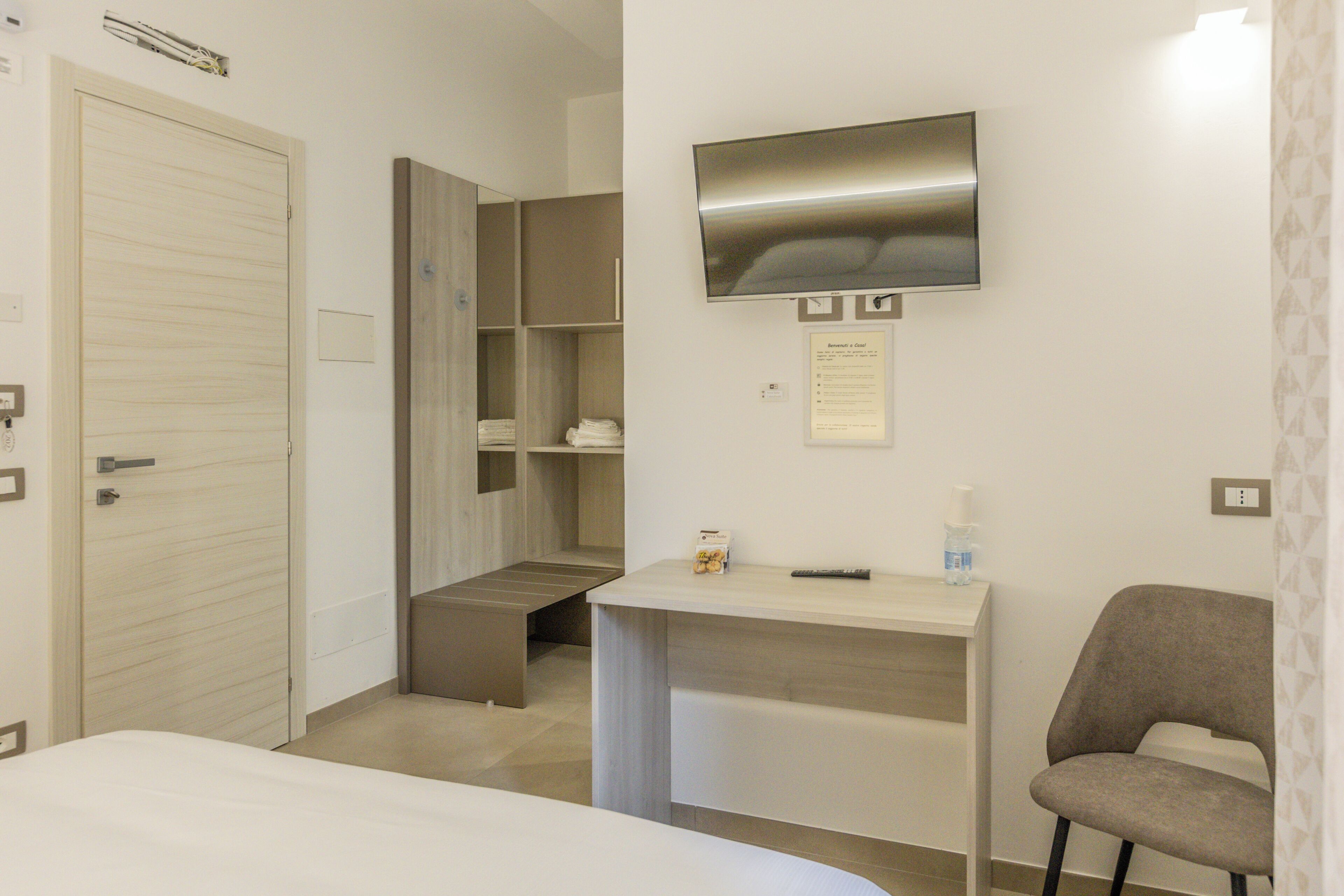 Habitació d'hotel amb un llit, escriptori, cadira, televisió i prestatges integrats.