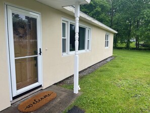 Ein Haus mit Eingangstür, Fußmatte und Rasenfläche.