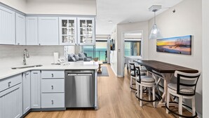 Une cuisine moderne avec des meubles blancs, un îlot central et un coin repas doté de chaises en bois.