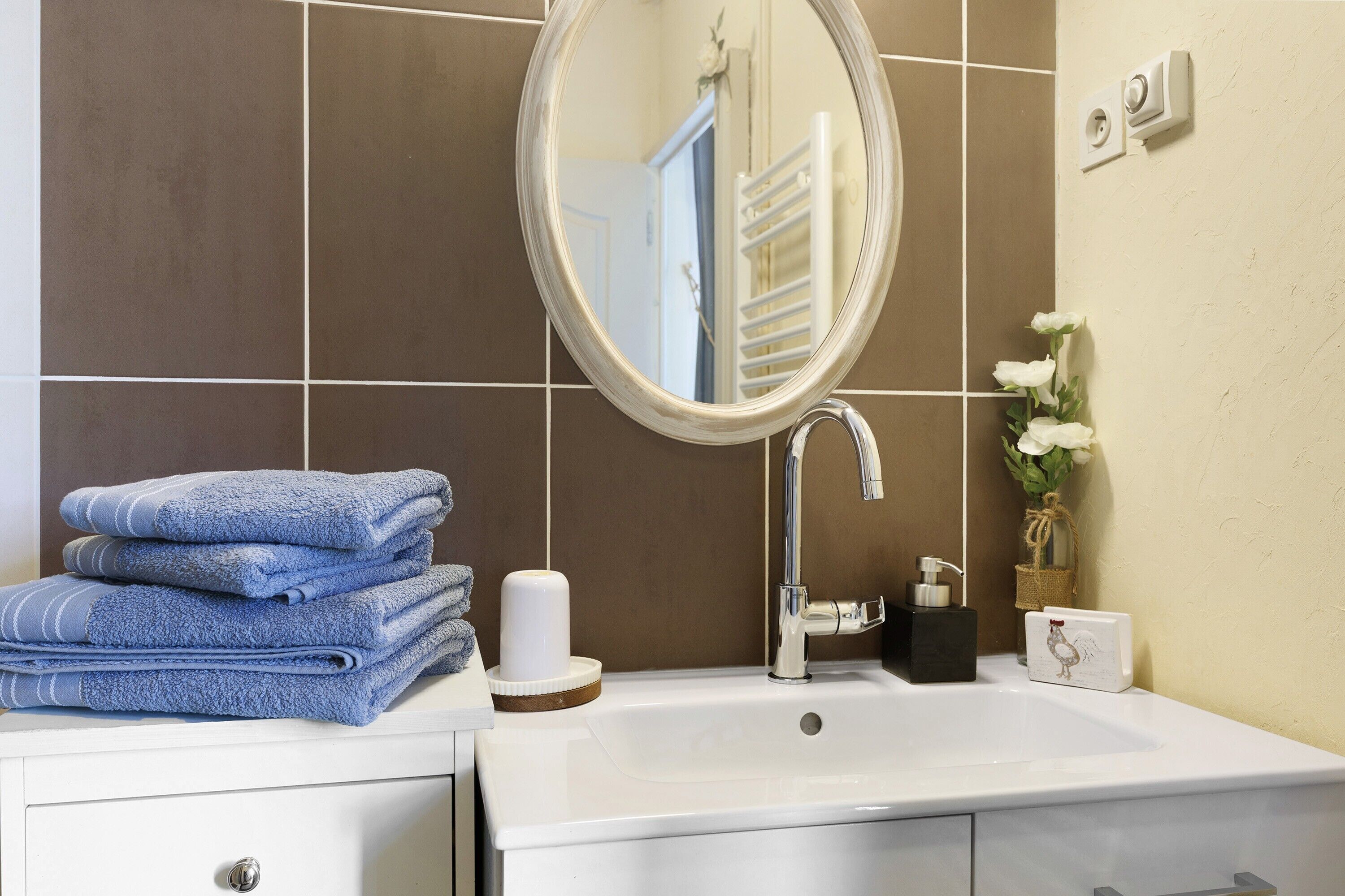 Un bagno con lavandino, specchio, pile di asciugamani e articoli da toilette.