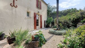 A house with a gravel pathway, potted plants, and a wooden deck.