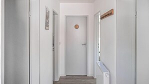 Un pasillo con paredes blancas, una puerta con un emblema circular y un radiador a la derecha.