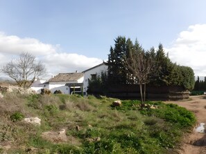 Edifici blanc amb teulada enrajolada, envoltat de vegetació i arbres.