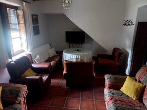 A living room with a sofa, armchairs, a small round table, and a television. - Rural House 'La Saucedilla' with Mountain Views, Private Pool and Wi-Fi (Archidona)