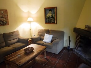 Un salon comprenant un canapé, un fauteuil, une table basse, une lampe, une cheminée et un tableau accroché au mur.