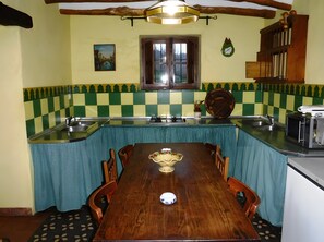 Une cuisine Ă©quipĂ©e dâune table Ă manger, de chaises, dâun Ă©vier, dâune cuisiniĂšre et dâun four Ă micro-ondes.
