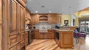 Una cocina con armarios de madera, una isla central y una zona de comedor con sillas.