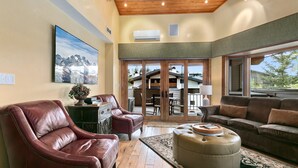 Un salón amplio con muebles de cuero, un ventanal y vistas al exterior.