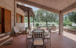 Eine Terrasse im Freien mit Esstisch und Stühlen, darüber eine Pergola.