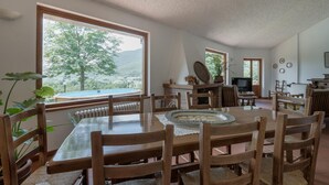 A dining area with a view of a pool and mountains, wooden furniture, and a fireplace. - Nice home in Configni (Configni)