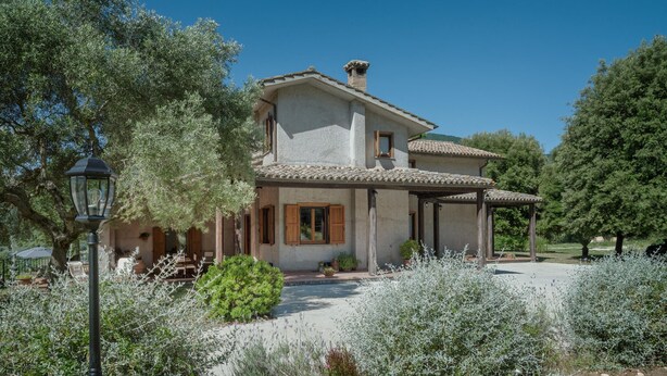 A two-story house with a tiled roof, a covered porch, and a garden with various plants. - Nice home in Configni (Configni)