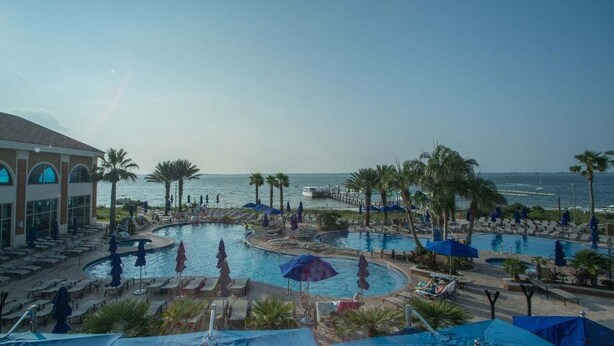Un resort con varias piscinas, palmeras y vistas al océano.