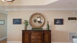 Una habitación con un espejo grande, un mapa mundial, un dibujo de barco y un aparador decorativo.