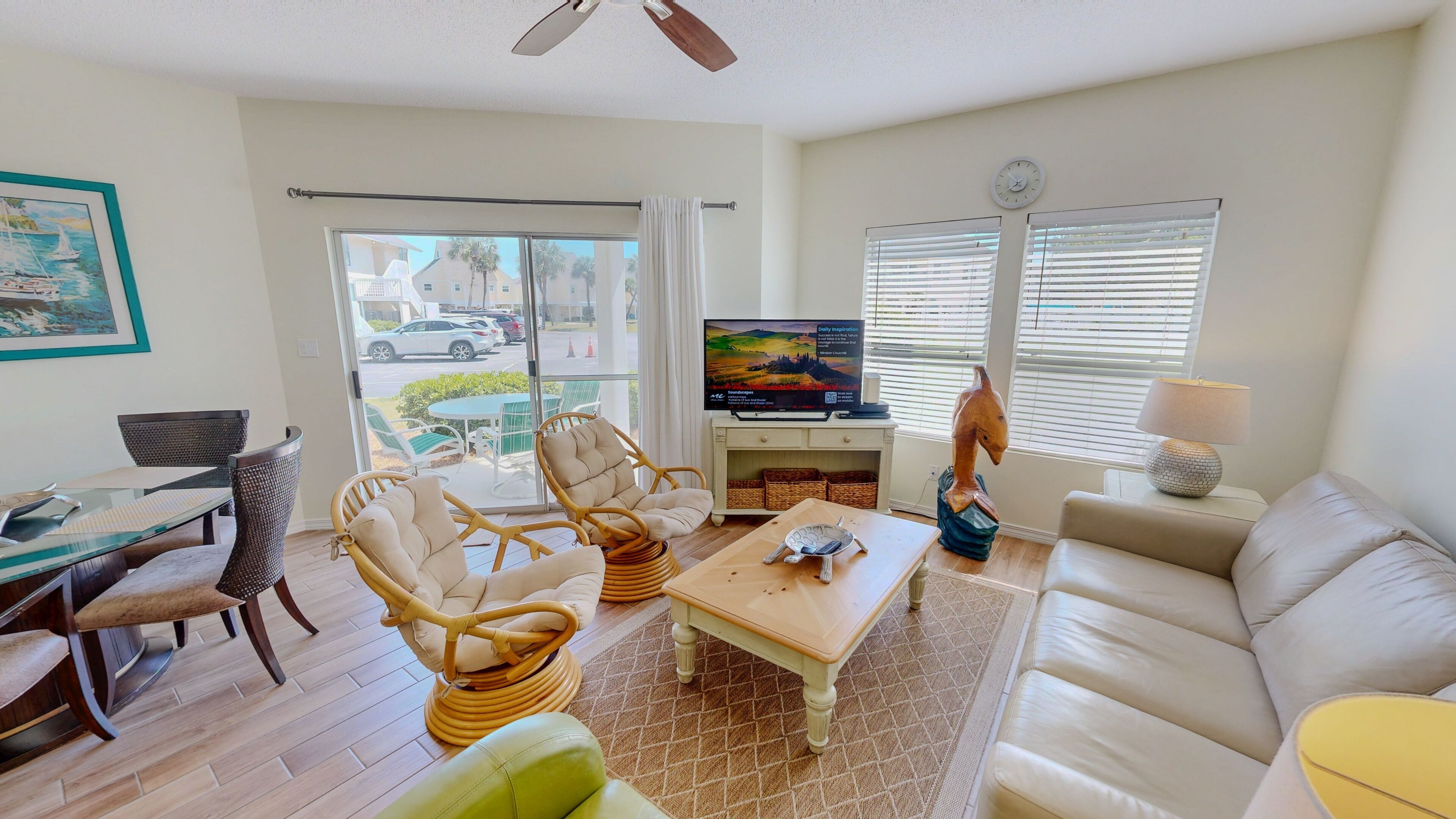 A living room with a sofa, chairs, a coffee table, a TV, and a window with blinds.