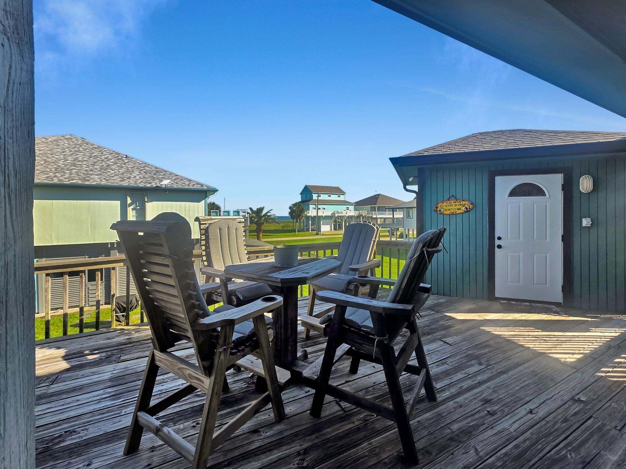 A wooden deck with outdoor furniture, a small shed, and a view of houses in the background.