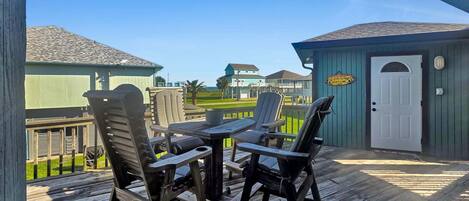 A wooden deck with outdoor furniture, a small shed, and a view of houses in the background.