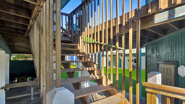 Una escalera de madera que lleva a una terraza cubierta con un letrero que indica las normas de la casa de playa.