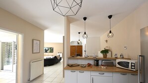 A modern kitchen with white cabinets, a wooden countertop, and a built-in microwave. - Villa des Amis with jacuzzi and swimming pool near the Alpilles and Luberon mountains (Sorgues)