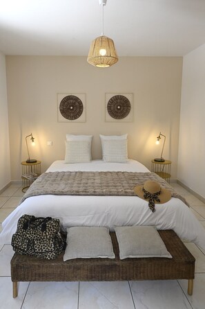 Ein Schlafzimmer mit einem großen Bett, zwei Wandlampen, einer gewebten Deckenleuchte und zwei Wandbildern.