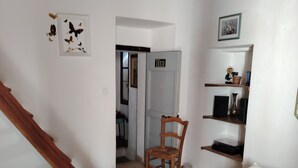 A room with a wooden staircase, a bed, a chair, a shelf with decorative items, and a door leading to another room. - Large, comfortable house with terrace overlooking the valley. (Sant'Andréa-di-Bozio)