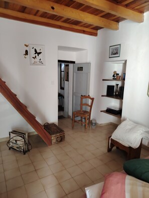 A room with a wooden staircase, a bed, a chair, a shelf with decorative items, and a door leading to another room. - Large, comfortable house with terrace overlooking the valley. (Sant'Andréa-di-Bozio)