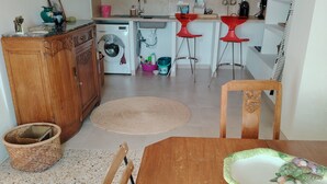A kitchen with a washing machine, a sink, and a dining area with a table and chairs. - Large, comfortable house with terrace overlooking the valley. (Sant'Andréa-di-Bozio)