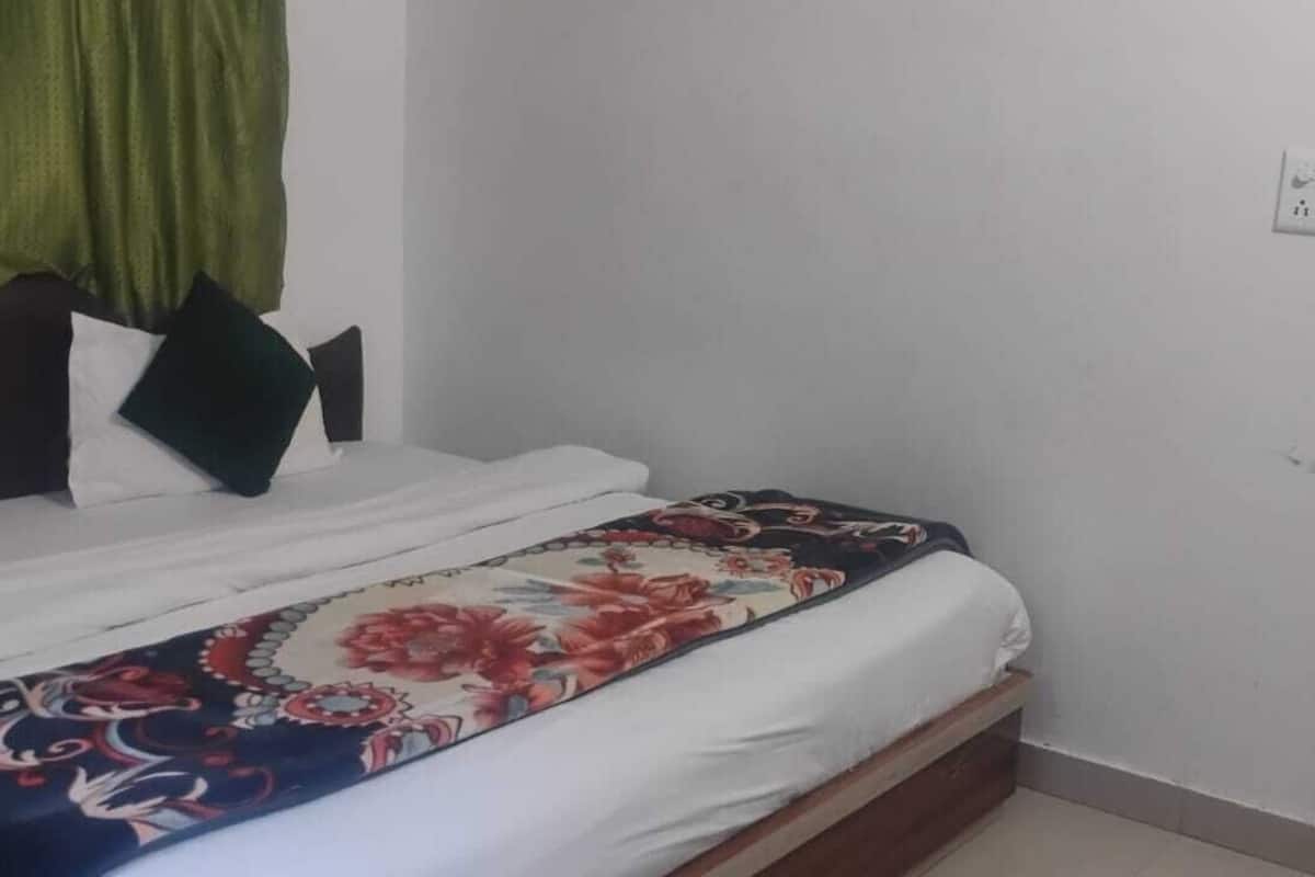 Une chambre à coucher comprenant un lit, une table de chevet, un miroir et une porte donnant sur une autre pièce.