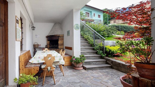A patio with a table, chairs, a stone fireplace, and potted plants.