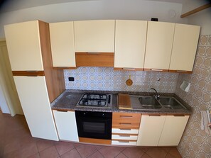 Cocina compacta con estufa a gas, horno, pileta y un salpicadero con diseño.