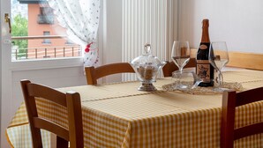A dining table with a checkered tablecloth, a bottle of champagne, two wine glasses, and a glass bowl with a lid.